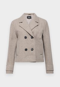 Dobbeltbrystet beige kort jakke med svarte knapper, spisse lapeller og lange ermer, laget av teksturert ull-lignende materiale.