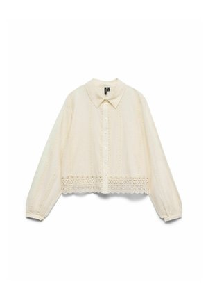 Blouse crème à manches longues, boutonnée sur le devant, col pointu, délicate bordure en dentelle le long de l'ourlet et motifs brodés subtils.