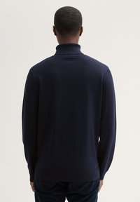 Granatowy sweter z golfem, z długimi rękawami, żebrowanym kołnierzem i gładką, miękką teksturą. Prosty design bez widocznych wzorów.