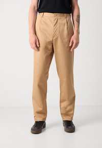 Beige, lightweight trousers with a straight cut, featuring a button closure, belt loops, and pockets. Worn with dark sneakers.