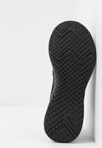 Suela de zapato de goma negra con un patrón de banda de rodadura en zigzag y un logotipo en relieve. Acabado brillante en los bordes, con acentos texturizados para un mejor agarre.