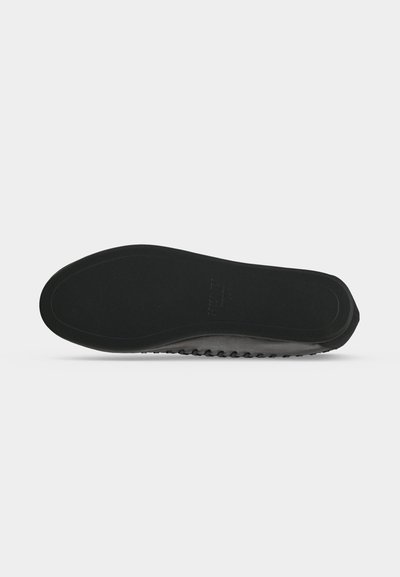 Semelle de chaussure noire avec un fond lisse et une légère bande de roulement visible sur le côté, présentée sur un fond blanc uni.