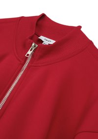 Rode zip-up jas met ribbelkraag en manchetten. Glad oppervlak met zilveren ritsdetail. Gelabeld "TWIST" aan de binnenkant van de kraag.