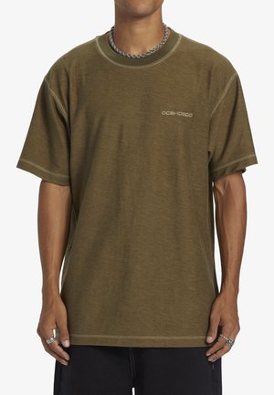 Olivegrünes T-Shirt mit kurzen Ärmeln und lockerer Passform, mit kontrastierenden Nähten und einem kleinen gestickten Logo auf der Brust.