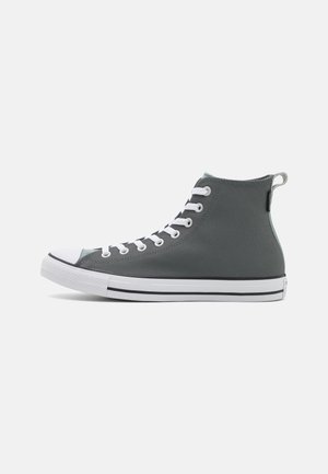 Højtop grå lærreds sneaker med hvid gummitåhætte, hvide snørebånd og hvid sål med sorte striber på en ensartet lys baggrund.