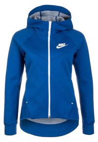 Blå Nike draghuva med huva, vit dragkedja och vit logotyp på bröstet, med en längre bakhem och sidofickor.