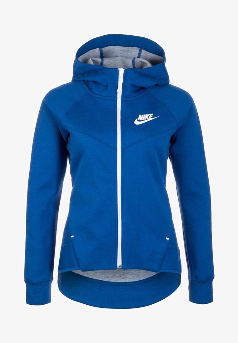 Modrá zipová mikina Nike se kapucí, bílým zipem a bílým logem na hrudi, s delším zadním lemem a bočními kapsami.