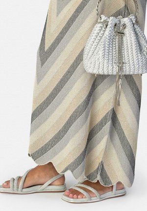 Beige en grijs gestreepte gebreide rok met gegolfde zoom, zilveren sandalen met bandjes in een platte hak, en een kleine zilveren handtas met trekkoord.