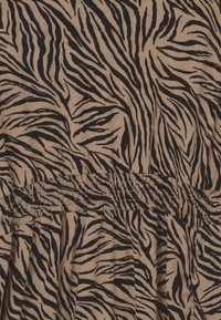 Tkanina w kolorze beżowym z czarnymi paskami tygrysa; posiada elastyczny ściągacz w talii, tworząc fakturowany, marszczony wzór w całej powierzchni.