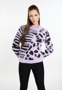 Lila, fuzzie Strickpullover mit schwarzen Tierdruckmustern. Der Pullover hat einen Rundhalsausschnitt und lange Ärmel, kombiniert mit schwarzen, engen Hosen.