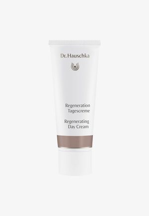 Weißer Tube mit schlankem Design, silbernen Akzenten und einem braunen Band. Der Text lautet "Dr. Hauschka Regeneration Tagescreme Regenerating Day Cream."