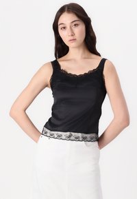 Črna satenasta majica s čipkastim robom ob dekolteju in robu, z nastavljivimi naramnicami in prilegajočim se dizajnom.