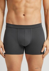 Donkergrijze aansluitende boxershorts van gladde stof met een tailleband en een contourpouch-ontwerp. Heeft gestikte zomen en minimale details.