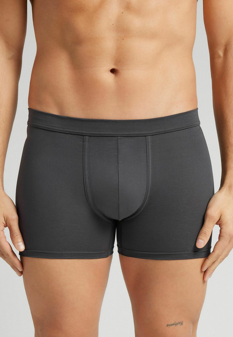 Donkergrijze aansluitende boxershorts van gladde stof met een tailleband en een contourpouch-ontwerp. Heeft gestikte zomen en minimale details.