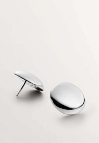 Pendientes de acero inoxidable plateados con una forma suave y redondeada y una superficie reflectante, que presentan un diseño simple y minimalista.