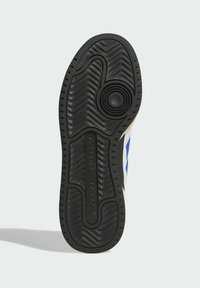 Black rubber sneaker sole featuring a textured pattern, circular detail in the center, and the Adidas logo embossed on the side.