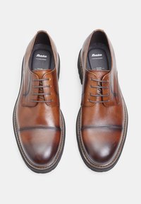 Scarpe da uomo in pelle marrone con finitura liscia, punta tondeggiante, design con lacci a sei fori e suole in gomma nera a contrasto.