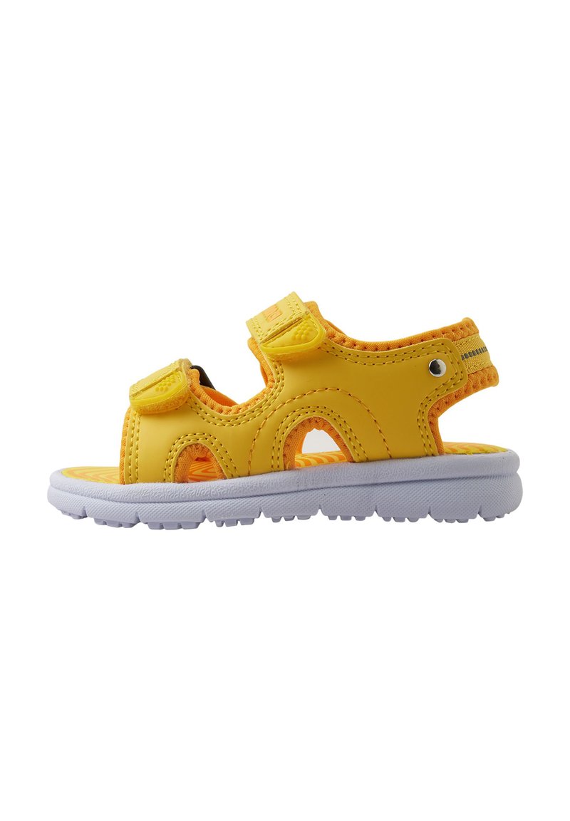 Gule barnesandaler med en fleksibel gummisåle, justerbare borrelåsremmer, utskåret design og oransje aksenter på sålen.