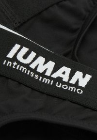 Schwarze Herrenunterwäsche mit einem breiten elastischen Bund, der den Text "IUMAN" und "intimissimi uomo" in kontrastierendem Weiß trägt. Glatte Stofftextur.