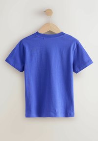 T-shirt à manches courtes en coton bleu vif, avec un col rond et une texture lisse. Suspendu sur un cintre en bois.