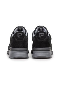 Schwarze Wildledersneaker mit grauen Gummisohlen, ausgestattet mit einem gepolsterten Kragen und einer Zuglasche hinten, mit einem Logo an der Ferse.