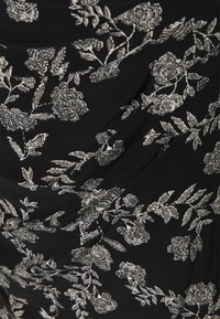 Czarna tkanina z białymi wzorami kwiatowymi; wyraźnie zaznaczona tekstura drapowania i liście. Miękki, gładki materiał o matowym wykończeniu.