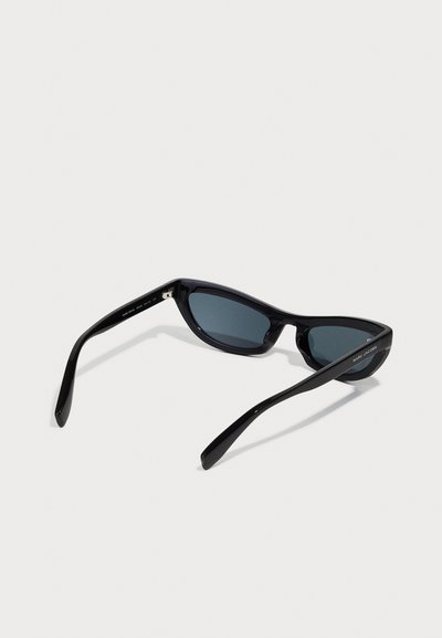 Lunettes de soleil noires avec une forme cat-eye arrondie et élégante. Monture en plastique brillante, verres sombres et un branding minimal sur le côté.