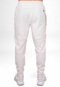 Helle graue Jogginghose mit schmalem Design, ausgestattet mit einem Kordelzugbund, strukturiertem Stoff und seitlichen Taschen. Sichtbare Akzentnähte.