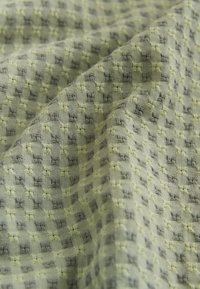 Tissu vert clair tissé avec un motif en grille texturé de petits carrés surélevés et une surface légèrement froissée.