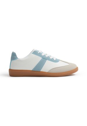 Zapatillas blancas y azul claro con una puntera beige, suela de goma texturizada y diseño con cordones. Presenta una franja lateral azul y detalles de acento.