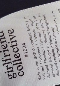 Étiquette de vêtement avec la marque « girlfriend collective », numéro de produit #1024, et texte multilingue indiquant fabriqué au Vietnam dans une usine certifiée SA8000.