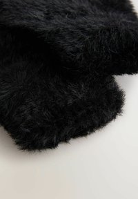 Schwarzer Kunstpelzstoff mit einer weichen, flauschigen Textur, der eine leicht unregelmäßige Form und dicht gepackte Fasern aufweist.