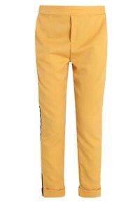 Žluté slim-fit kalhoty s černými bočními pruhy a ohrnutými nohavicemi, na bílém pozadí.