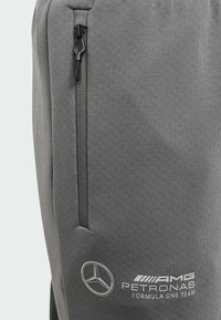 Grå träningsbyxor i flexibelt material, med en ficka med dragkedja och tryckt logotyp för Mercedes AMG Petronas Formula One Team.