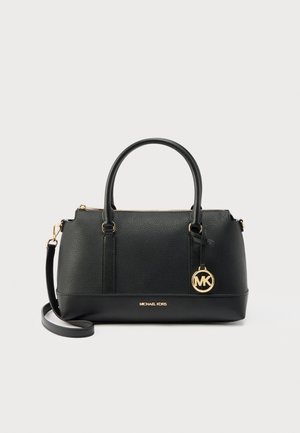 Μαύρη υφασμάτινη τσάντα Michael Kors με διπλές λαβές, αποσπώμενο ιμάντα ώμου, χρυσό μπρελόκ λογότυπο και κλείσιμο με φερμουάρ σε ανοιχτό φόντο.