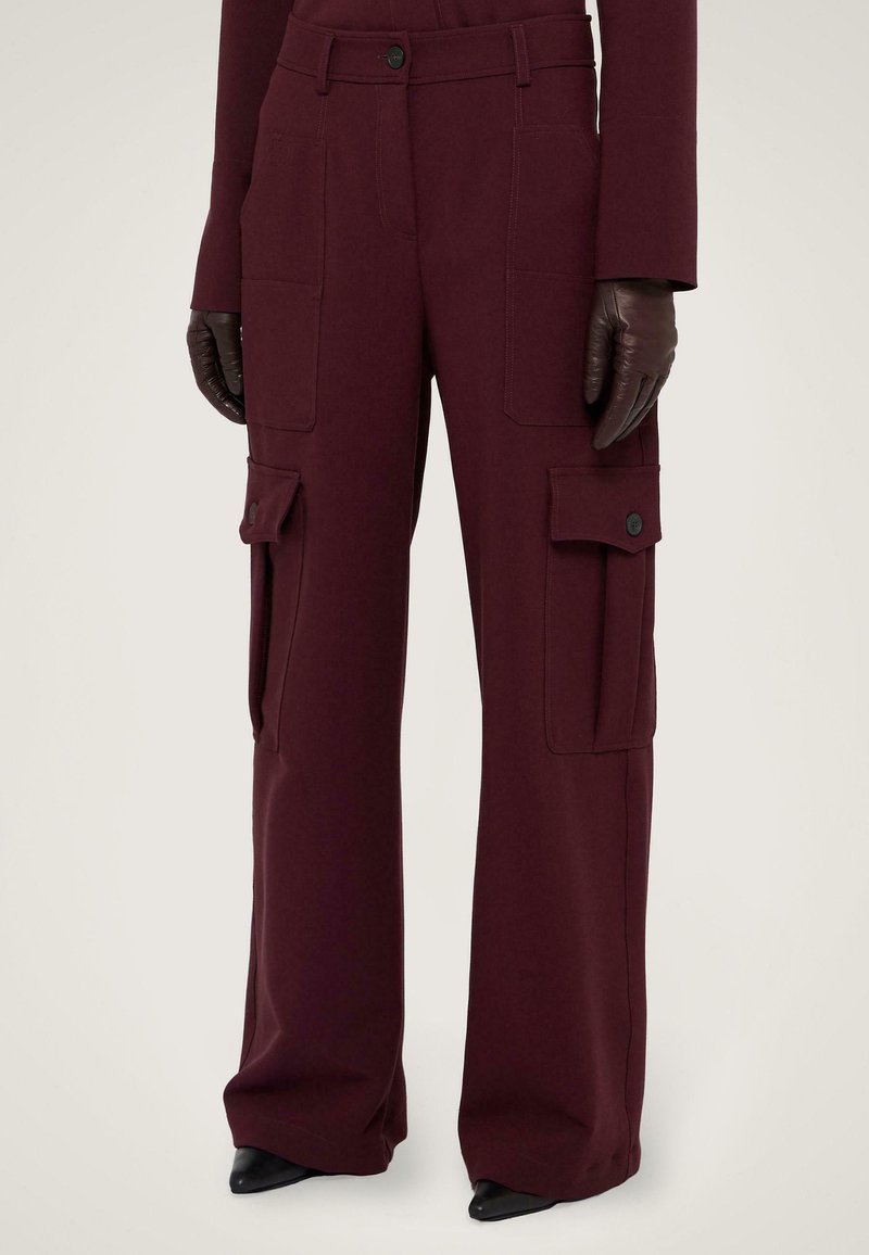 Bordeaux cargobroek met brede pijpen, gemaakt van een katoenmix, met zijzakken en drukknoopsluitingen. Gecombineerd met aansluitende bruine leren handschoenen.