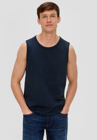 Marineblaues ärmelloses Tanktop aus Baumwolle, mit rundem Ausschnitt und lässiger Passform, kombiniert mit dunkelblauen Jeans.
