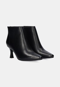 Botas de cuero negras hasta el tobillo con un diseño de punta afilada, tacón alto delgado, textura suave y una silueta minimalista sin adornos.