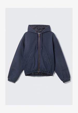 Marineblauw capuchonjack met een ritssluiting aan de voorkant, elastiek bij de manchetten en zoom, en twee zijzakken. Gemaakt van een zachte, duurzame stof.