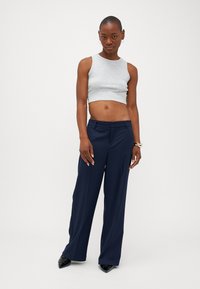 Top cropped cinza combinado com calças largas azul-marinho. As calças apresentam uma textura suave, e o conjunto é finalizado com sapatos pretos de bico fino.