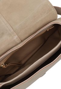 Beige suède handtas met een gladde textuur, voorzien van een ritsvak en stoffen voering. Van binnen heeft het meerdere compartimenten voor organisatie.