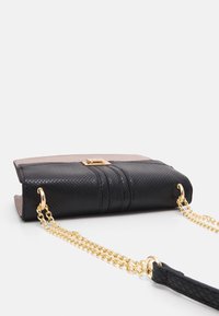 Czarna skórzana torebka o teksturowanym wykończeniu, z złotym łańcuszkiem na ramię i brązową skórzaną klapą. Z wyposażona jest w złote zapięcie.