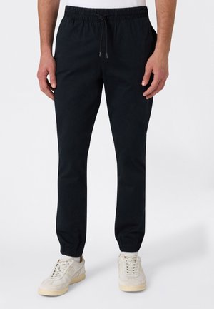 Zwarte taps toelopende joggers van zacht stof, voorzien van een elastische tailleband met trekkoord en elastische boorden bij de enkels.