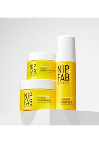 La ligne de soins NIP+FAB Barrier comprend trois récipients jaunes : un baume nettoyant, une crème de nuit et un sérum, chacun avec des accents et du texte blancs.