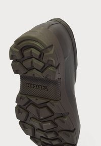 Talpa cizmei de exterior negre are un model de tread rugos și un accent de marcă, conceput pentru tracțiune și stabilitate pe diverse terenuri.