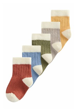 Pięć par prążkowanych skarpet w kolorach czerwonym, niebieskim, zielonym, szarym i żółtym, każda z białymi mankietami, piętami i palcami, ułożonych ukośnie na białym tle.
