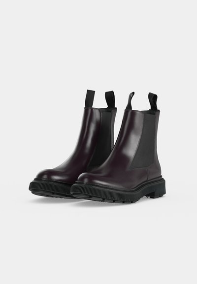 Bottes Chelsea en cuir violet foncé avec panneaux latéraux élastiques noirs, semelles épaisses en caoutchouc noir et languettes à l'avant et à l'arrière.
