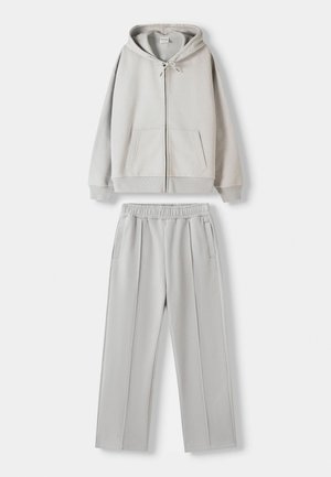 Grey hooded sweatshirt with front pockets and drawstrings, paired with matching grey elastic-waist jogger pants featuring side pockets.