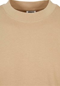 Pull beige col rond en tissu tricot côtelé avec coutures visibles et petite étiquette visible à l'intérieur du col.