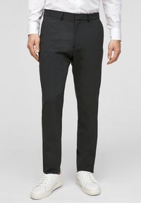 Czarne, dopasowane spodnie z płaskim przodem, szlufkami na pasek i slim fit, połączone z białymi trampkami. Gładki materiał i czysty design.